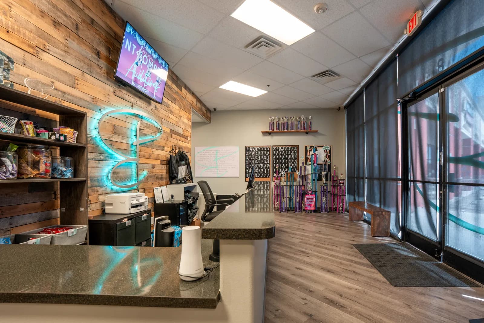 Reception detail at Evolve Dance Center showing the neon Evolve E and trophy display
